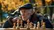An old man sits on a park bench, lost in thought as he stares at a chessboard.