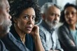 © Larisa - A group of diverse adults engaged in a serious discussion, with a woman looking concerned in the foreground.