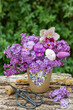 romantischer Blumenstrauß mit Fliederblüten, Hornveilchen, Lenzrose, Tulpe und Maßliebchen im Torftopf