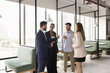 © fizkes - Multiethnic happy office friends meeting in office hall, talking, chatting, laughing, having fun, pointing index fingers at each other in got you gesture, enjoying friendly discussion