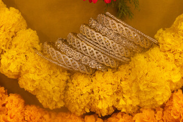 Sticker - stone studded intricate bangles spread on yellow marigold flowers