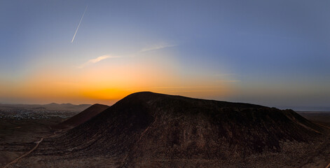 Wall Mural - Beautiful aerial sunset image over Volcan Calderon Hondo volcanic crater silhouetted against the setting sun and skyscape near Corralejo, Fuerteventura, Canary Islands, Spain