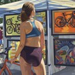 A toned woman in a snug workout top and cycling shorts, admiring artwork at a street fair. 