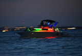 Fototapeta  - Motorówka podświetlona kolorowymi lampkami płynąca na morzu karaibskim po zachodzie słońca