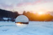 Closeup crystal sphere with scenic cloudy sunset on the background. Winter in mountains. Balance in life concept
