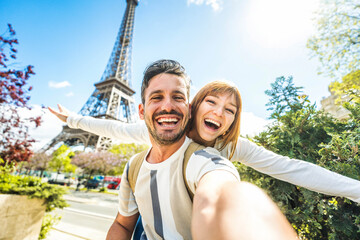 happy couple of tourists taking selfie picture in front of eiffel tower in paris, france - travel an