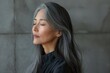 A serene middle-aged woman with beautiful gray hair closes her eyes in a peaceful, meditative state