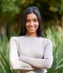 Poster - Girl, portrait and smile with arms crossed in park on vacation, relax and outdoor in nature for adventure. Woman, happy and confident person with pride, garden or holiday in spring by trees in Mumbai