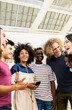 Vertical photo of multiracial group of young teenage people laughing together outdoors. Friendship concept.