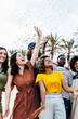 © Xavier Lorenzo - Vertical photo of young multiracial hipster people having fun in summer party celebration. Diverse friends laughing and celebrating all together while throwing confetti at weekend event outdoors