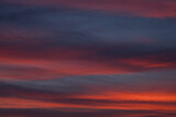 Fototapeta Koty - Dramatic sunset with vibrant clouds lit by a sun