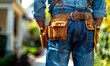 Worker with tool belt standing in front of house