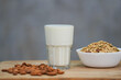 Pour milk into the glass placed on the table. Contains almond seeds Place on the wooden table surface and the granula seeds and grains in the bowl.