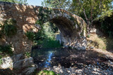 Fototapeta  - A stone, historic bridge over a mountain stream on the island of Crete
