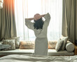 Hotel relaxation on lazy day with Asian woman take it easy waking up from good sleep on bed in morning resting in comfort bedroom, having happy, work-life quality balance lifestyle