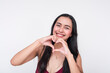 Young Asian woman in maroon dress making heart shape with hands, white background