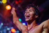 Fototapeta  - An enthusiastic young man is celebrating in a lively atmosphere with colorful lights, possibly at a party or event