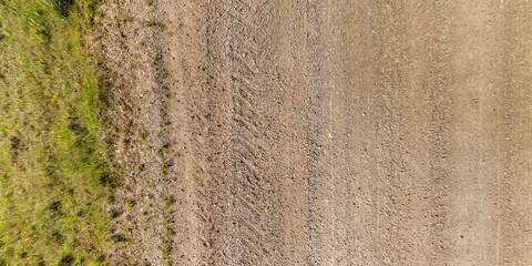 Wall Mural - view from above on texture of wet muddy road with tractor tire tracks in countryside