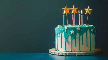 Wall Mural - Whimsical white birthday drip cake adorned with teal ganache, star toppers, and colorful candles on dark blue background - festive celebration concept