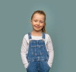 Little girl in denim overalls on a blue background.