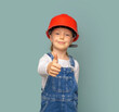 Little girl worker in a safety helmet with a tool on a blue background.