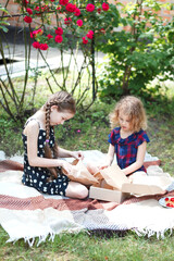 Two girls are creating ceramic mosaic pieces in the garden. 