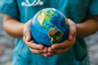 A person is holding a globe in their hands. The globe is blue and has a gold color