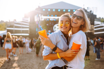 Wall Mural - Beach party. Two young woman with beer at music festival. Summer holiday, vacation concept.