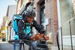 © Marko Geber - Delivery man on a bicycle wearing a helmet and backpack checking his phone on a city street