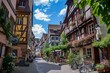 A cobblestone street in an European village lined with historic buildings and bustling with activity, Bustling marketplace surrounded by medieval buildings, AI Generated