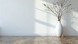 A white vase with a branch in it sits on a wooden floor. The vase is the only object in the room, and the space is empty. The vase and the branch create a sense of calm and serenity