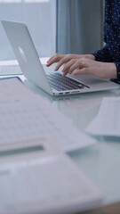 Business woman is working with laptop computer while sitting at the glass table in home office. Female entrepreneur typing information, hands closeup