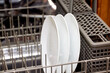 Close up of white ceramic plates in the lower rack of a dishwasher