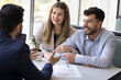 © fizkes - Happy young diverse husband and wife consulting legal adviser, realtor, talking, listening to consultant at meeting, sitting at table with paper document, discussing loan mortgage agreement