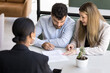 © fizkes - Focused married couple signing document, insurance agreement, closing real estate deal at meeting with agent, taking loan, mortgage after consulting lawyer, realtor, law advisor