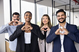 Fototapeta Tulipany - Multiethnic business team of happy coworkers in formal clothes making hand heart gesture, promoting support, charity, volunteering, looking at camera, smiling for office portrait