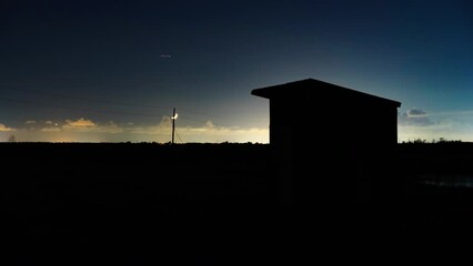 Wall Mural - Lockdown Time Lapse Silhouette Of Structure On Dark Landscape Against Crescent Moon Moving In Clouds At Night - Jefferson County, Texas