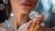© Sittipol  - A woman's hand holding a large diamond in front of her face