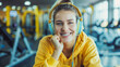 Cheerful woman sitting in gym and listening to music