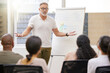 © peopleimages.com - Businessman, coach and presentation with team in seminar, meeting or workshop for training staff at office. Mature man or mentor talking to group of employees with whiteboard for business discussion