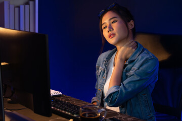 Young beautiful Asian businesswoman taking break with stretching body with ache symptom for relaxing muscle after finishing overworked load report at neon light modern office at night time. Stratagem.