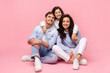 © Home-stock - Positive daughter hugging her parents from back, posing together on pink studio background, smiling to camera. Family expressing happiness
