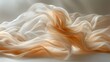   An abstract image of a white and orange fabric fluttering in the wind against a pristine white backdrop Soft, flowing fabric is prominently displayed in the foreground