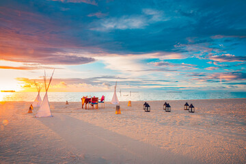 Romantic destination dining, couple anniversary romance celebration. Wedding ceremony on sunset beach. Love luxury arrangement togetherness dinner table candles on island shore. Amazing sky sea view