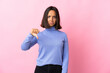 © luismolinero - Young latin woman isolated on pink background showing thumb down with negative expression