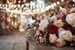 A rustic wooden table adorned with an arrangement of peonies in full bloom, ranging from pure white to deep burgundy, surrounded by vintage wedding decor in a dimly lit barn. 