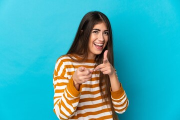 Wall Mural - Young caucasian woman isolated on blue background surprised and pointing front