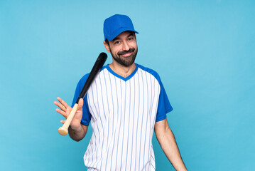 Wall Mural - Young man playing baseball over isolated blue background smiling