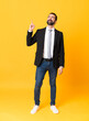 Full-length shot of business man over isolated yellow background pointing up and surprised