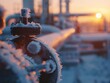 Close-up of a frosted industrial valve with hoarfrost crystals against a blurred sunrise backdrop, conveying coldness in an industrial setting.